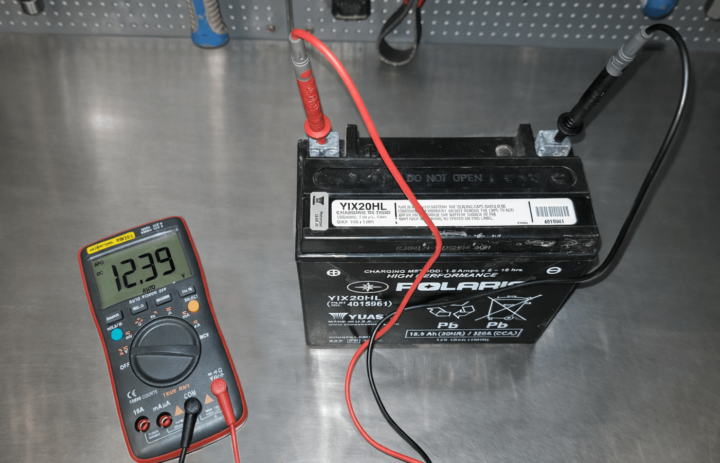 Meranie napätia motocyklovej AGM batérie YIX20HL digitálnym multimetrom na nerezovom pracovnom stole
